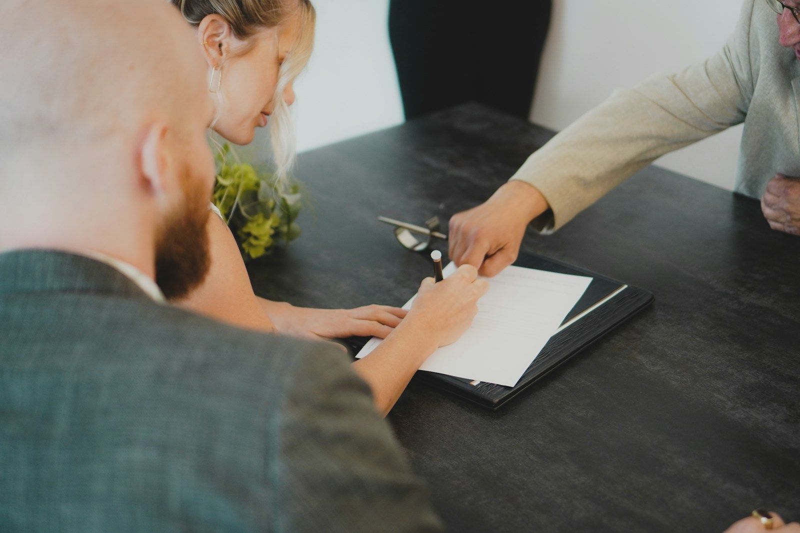 Dos personas firmando un documento sobre un escritorio