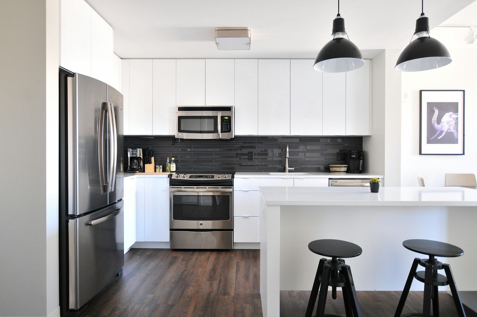 Cocina blanca con frigorífico y horno de acero inoxidable e isla central