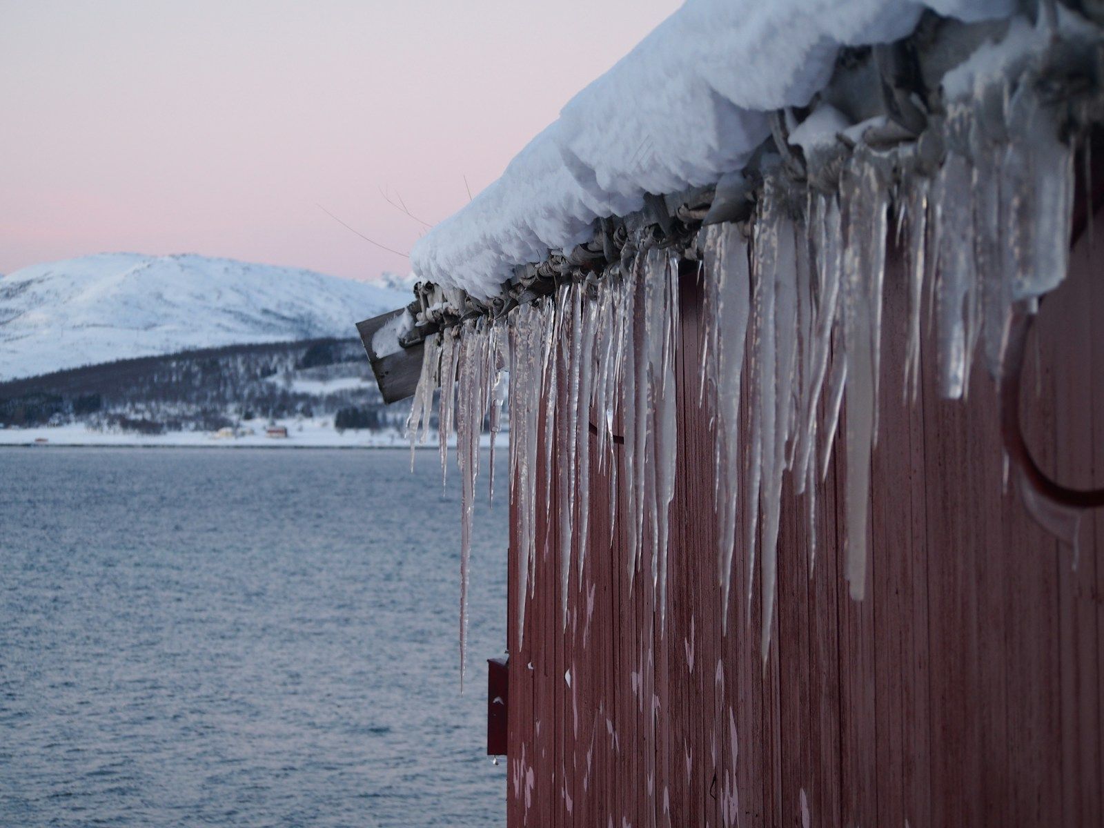 Long icicles hanging from the edge of a snow-covered roof