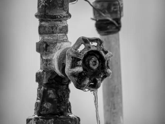 An old faucet with a bead of water forming at its end