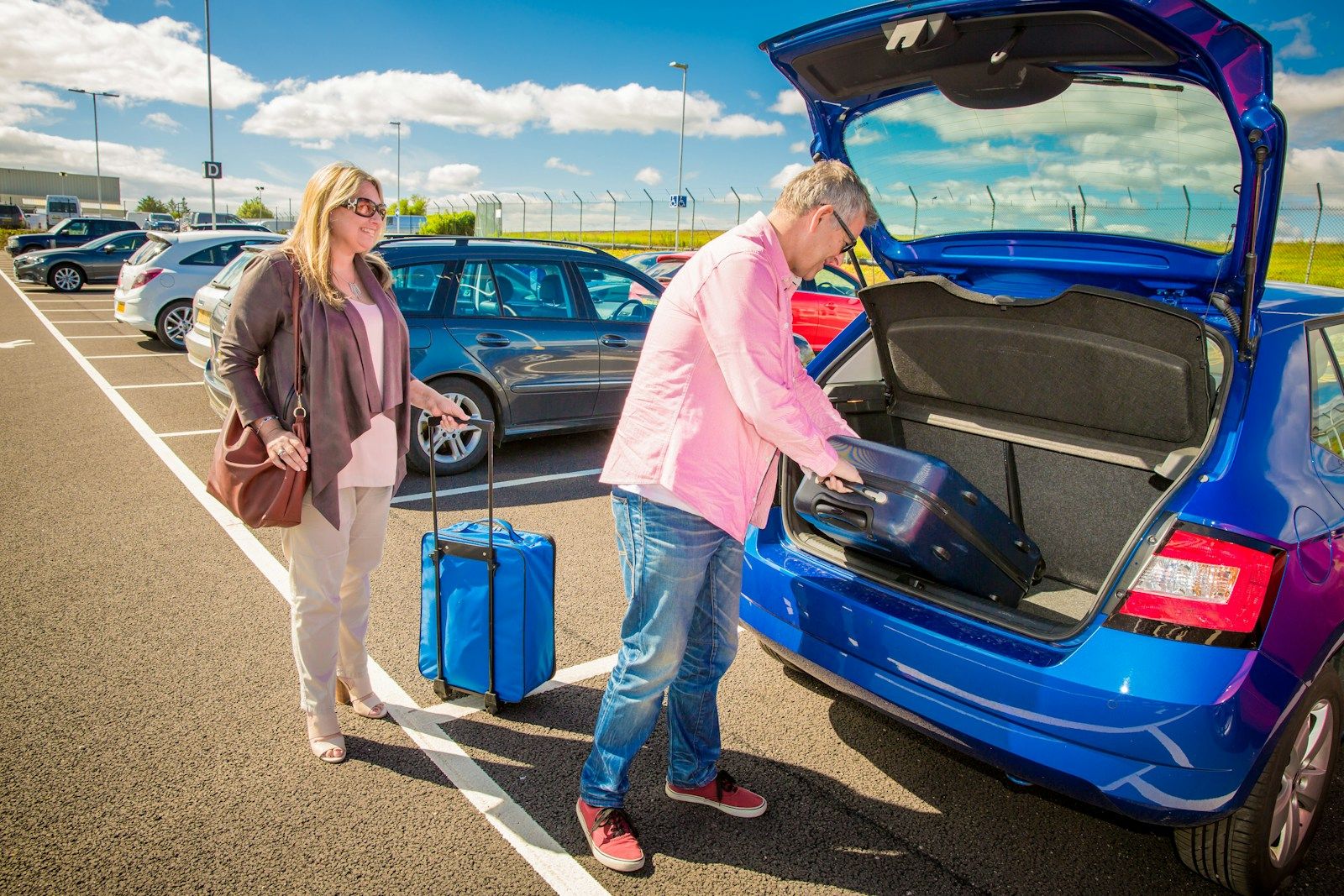 Dos personas cargando maletas en un coche azul