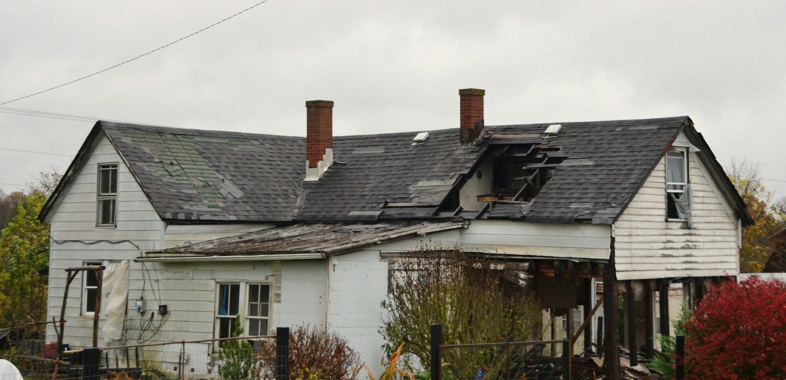 Weathered house with a large hole in its shingled roof