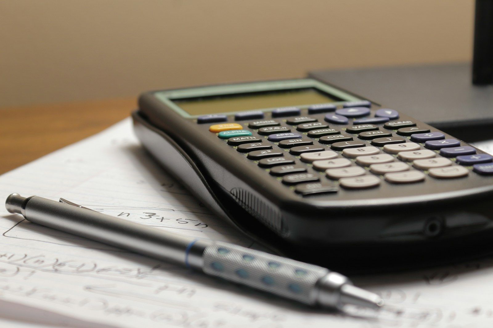 Calculator and pen resting on handwritten paper