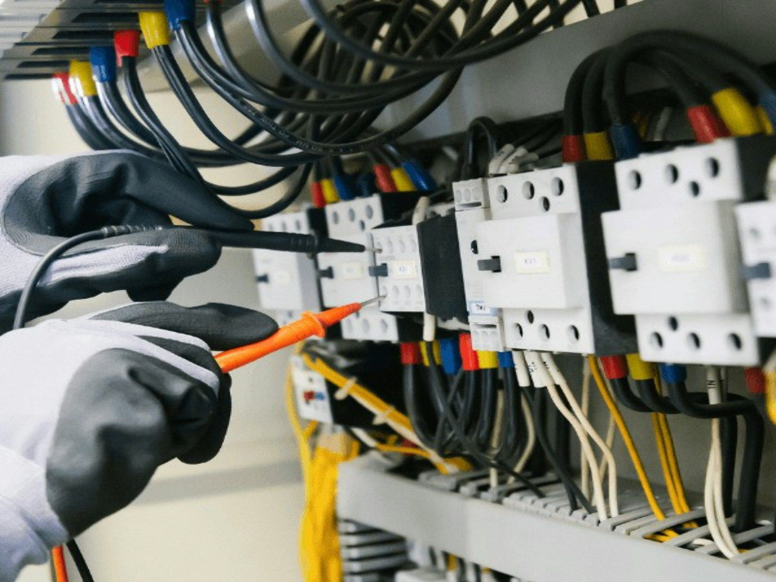 Electricista comprobando un cuadro eléctrico abierto con un multímetro