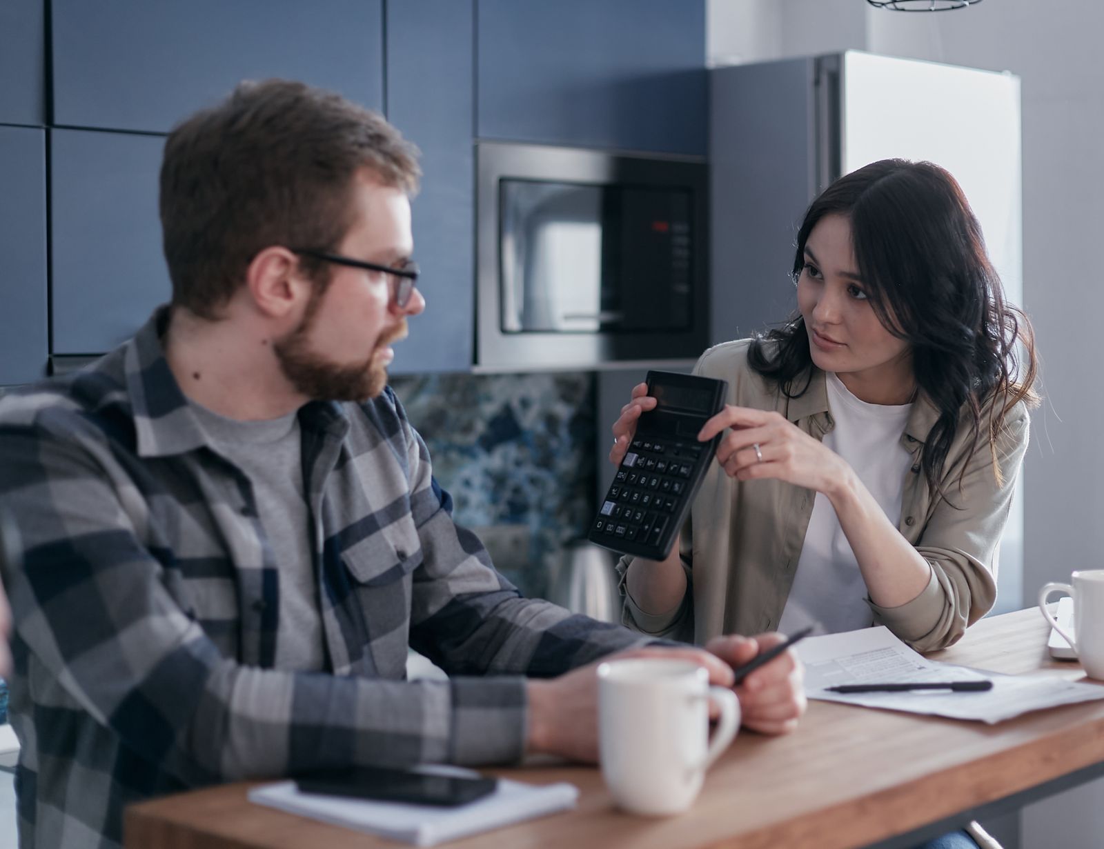 Couple discussing documents and a calculator at a table