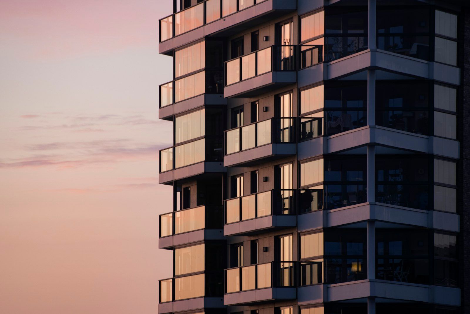 Edificio moderno de apartamentos con balcones de cristal al atardecer